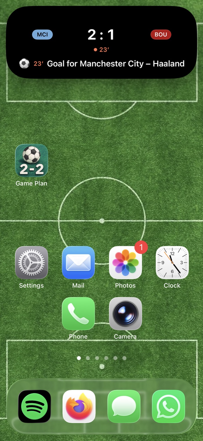 An iPhone Home Screen with the live score shown in the Dynamic Island